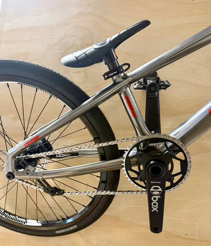 Bicycle frame with chain and gear on a wooden floor