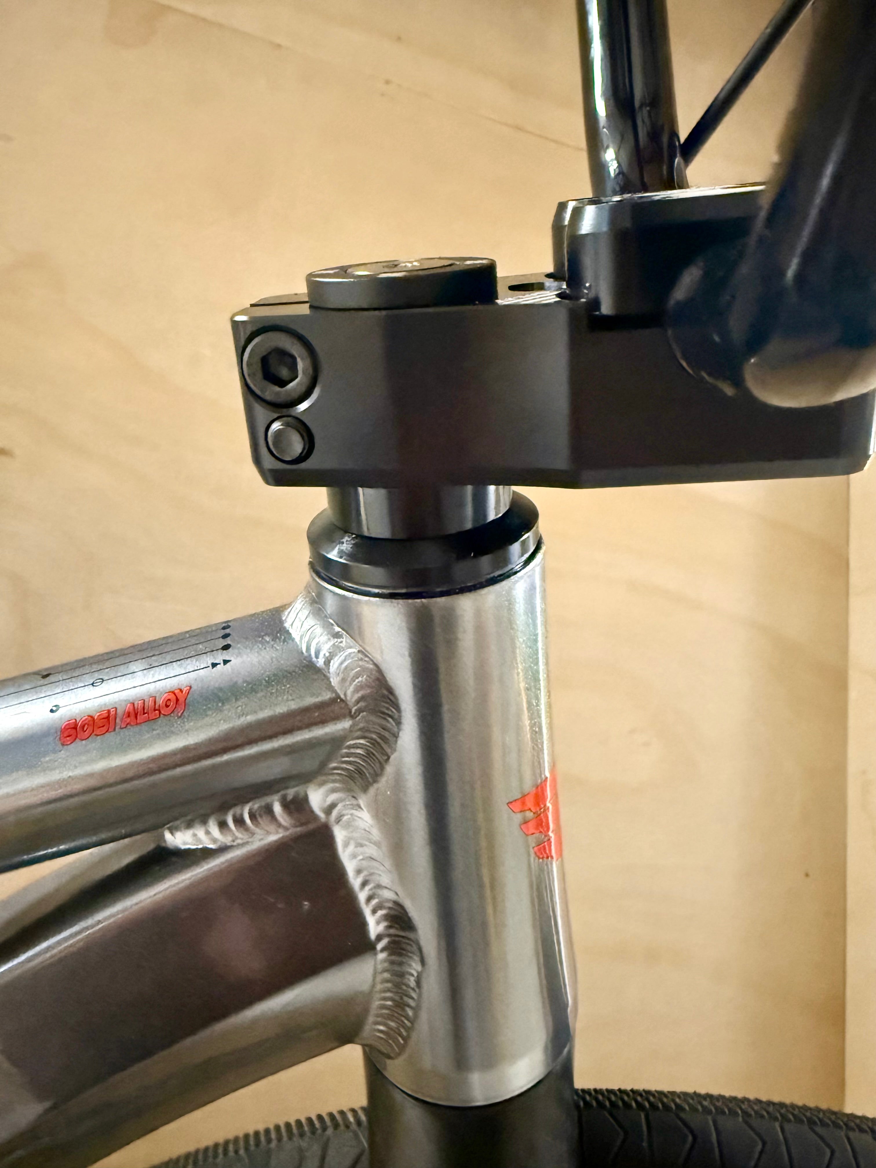 Close-up of a bicycle frame with 'Alloy' branding on a wooden background